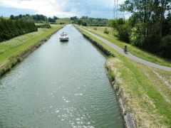 La Voie Verte V52 longe le canal de la Marne au Rhin, et cette photo est prise au niveau de Hertzing en direction de Gondrexange. Les cyclistes circulent avec les péniches touristiques.